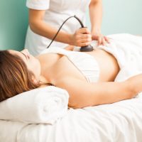 terapeuta-femenina-dando-tratamiento-reductor-reafirmante-cliente-centrandose-su-vientre